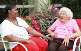 a nurse and an elderly woman are sitting in armchairs and laughing